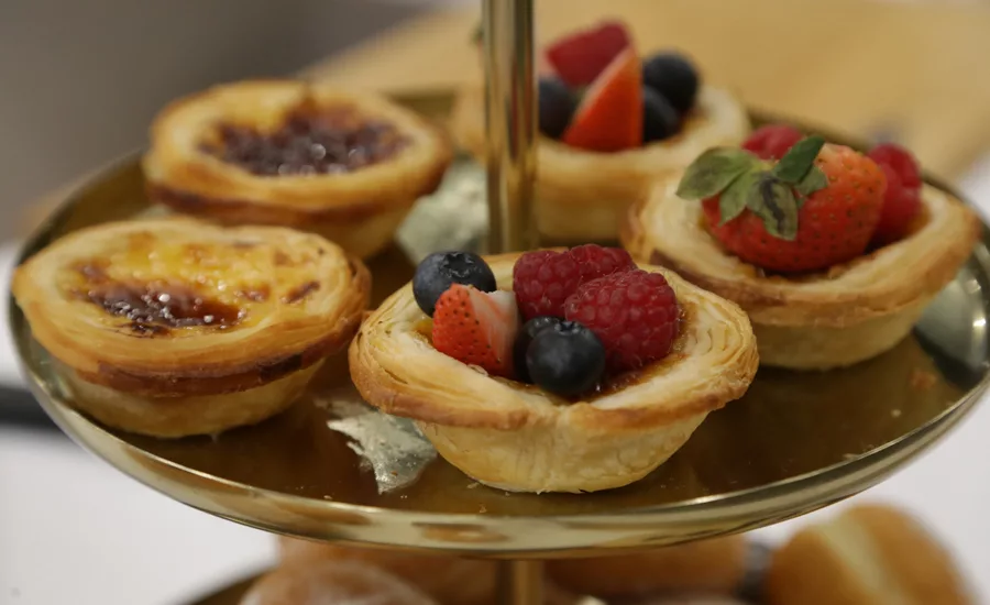 A tier with pastries with fruit and a crème brulee topping.