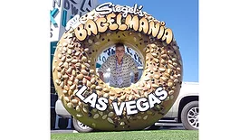 Woman hiding behind giant bagel-shaped Siegel’s Bagelmania sign