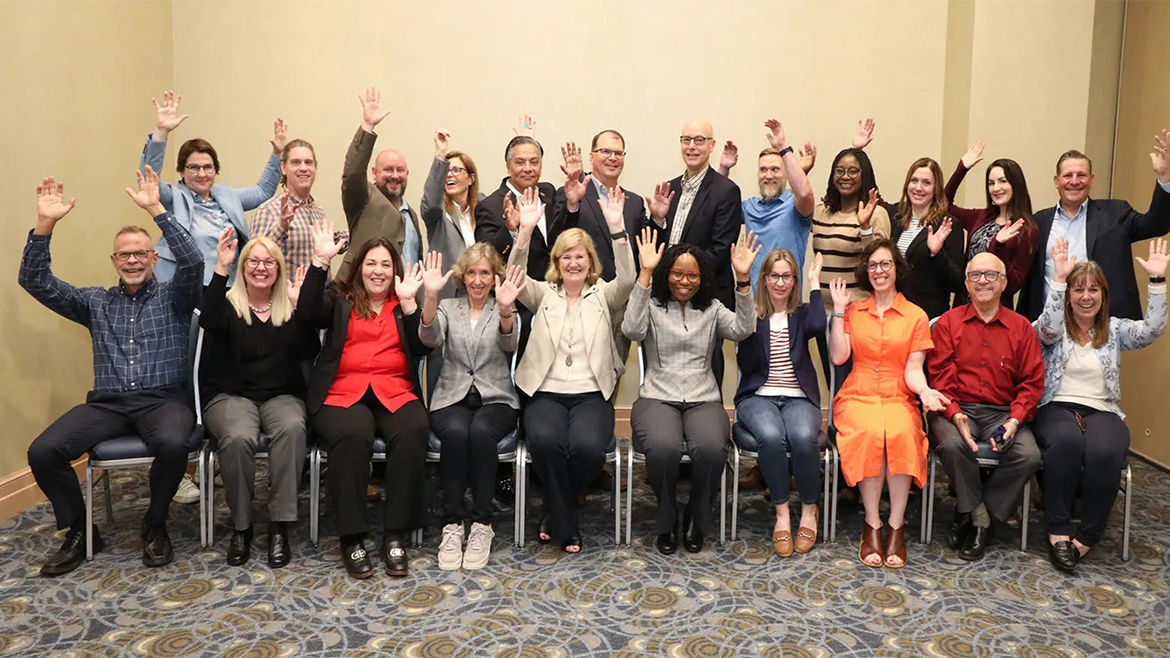 Two rows of people waving at the camera