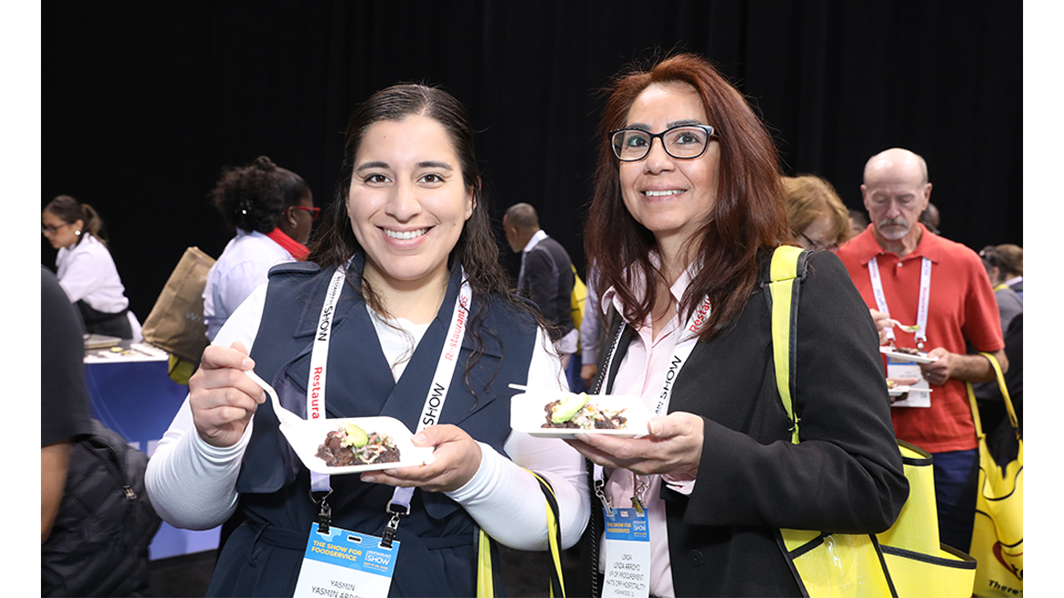 two individuals holding plates of food at an event.