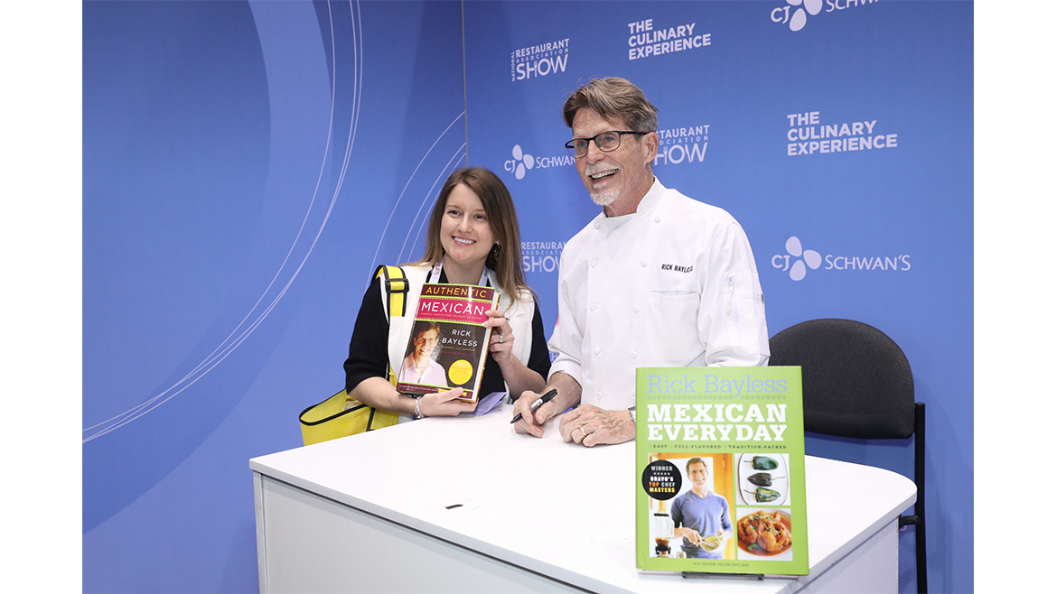  award-winning chef Rick Bayless signing books at a culinary industry event. 