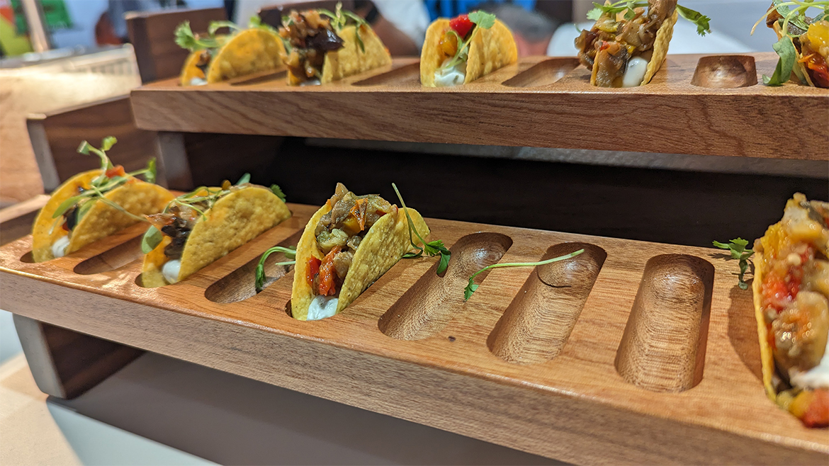 This image features a multi-tiered wooden display stand showcasing several small tacos