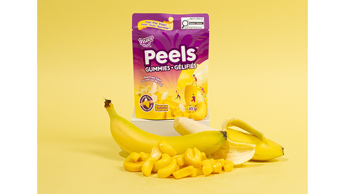 A yellow and purple bag of banana peelable gummies with bananas in front.