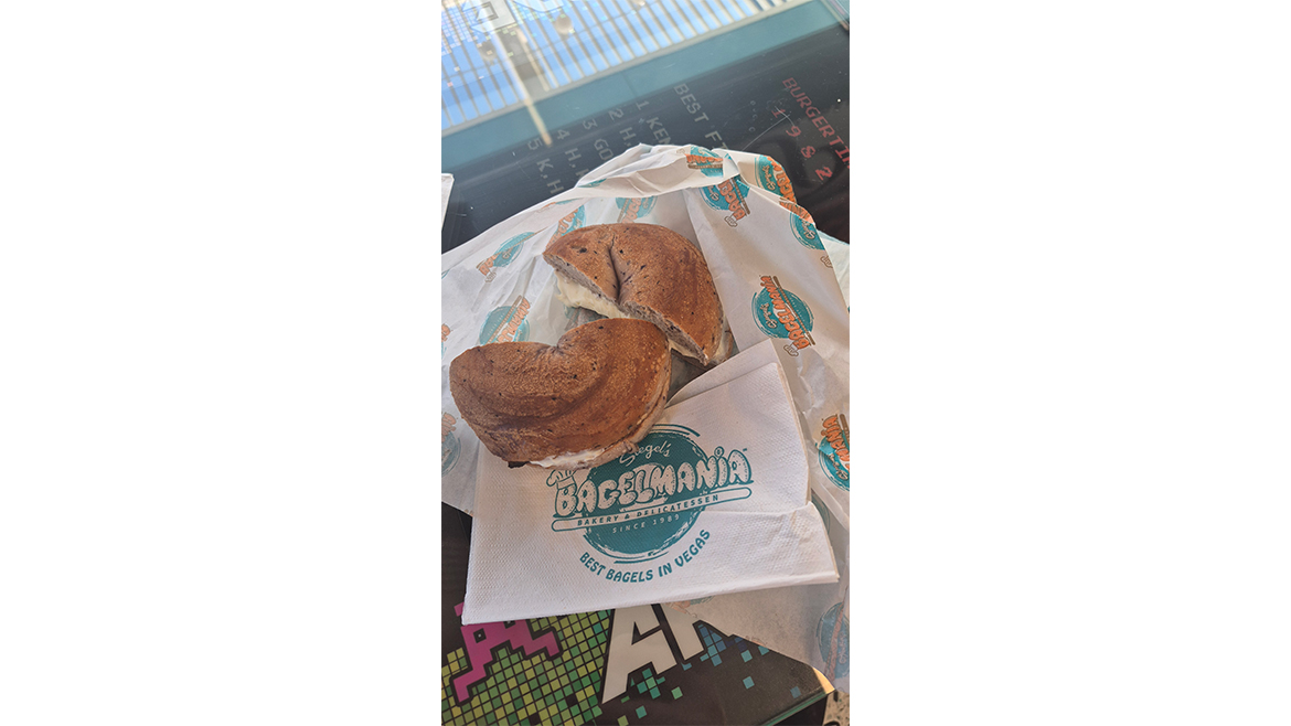 Bagel with cream cheese cut in half on wax paper