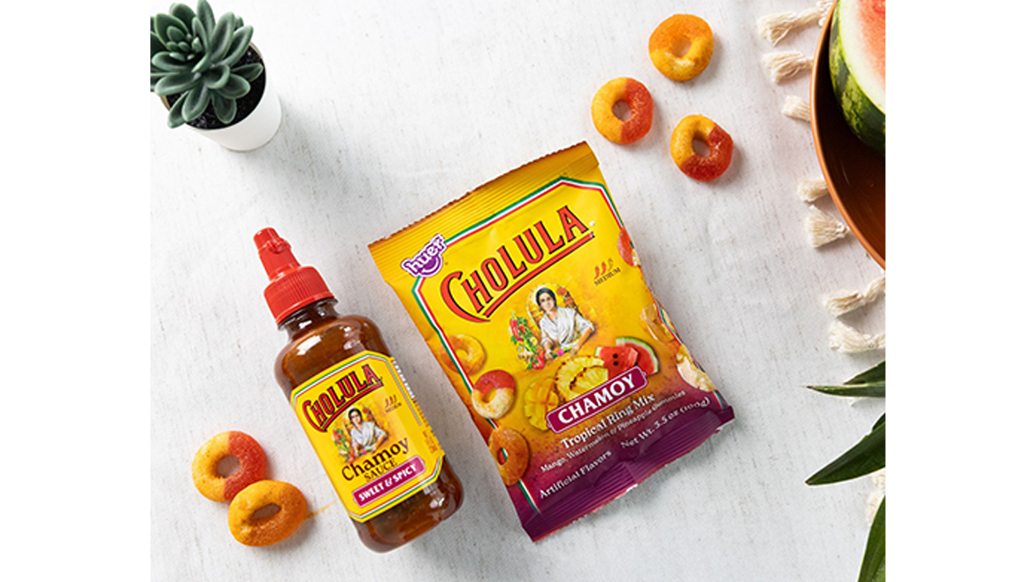 A bottle of Chamoy sauce next to a yellow bag of Chamoy gummies.