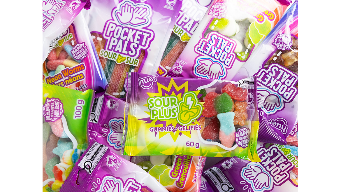 A pile of sour gummies in green, red, and purple packaging.
