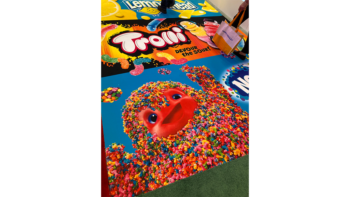 The floor at the 2025 Sweets & Snacks Expo, with colorful Trolli and Nerds images.