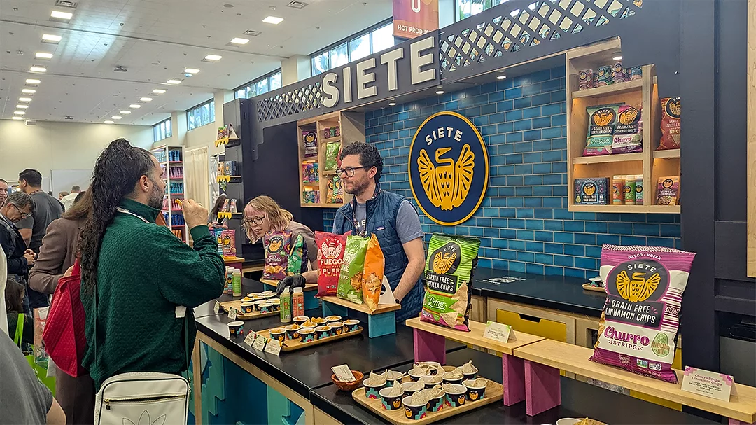 Man at Siete tradeshow booth talking to woman