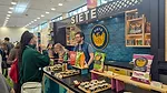Man at Siete tradeshow booth talking to woman 