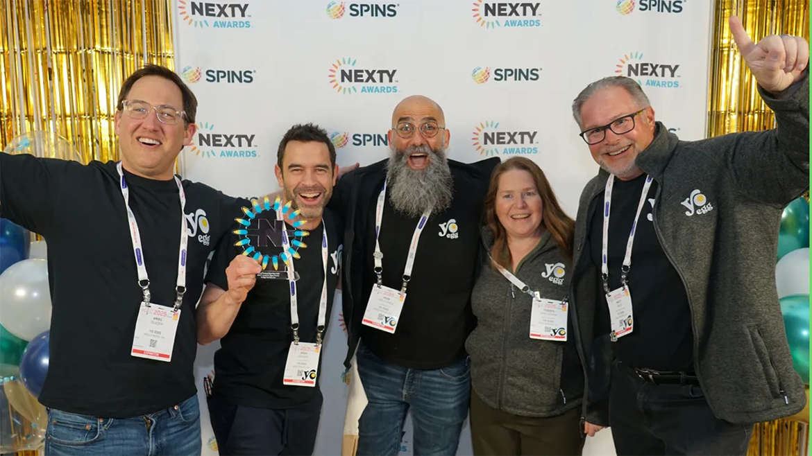Five people wearing show badges in front of NEXTY and Spins backdrop