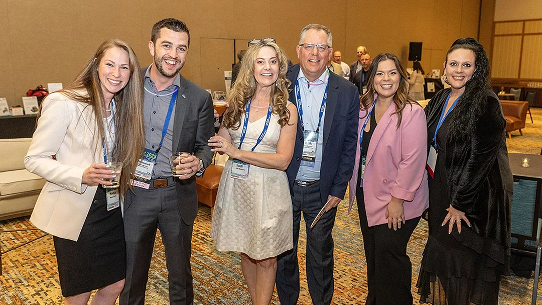 This image shows a group of people smiling and posing together, likely at a professional conference or networking event.