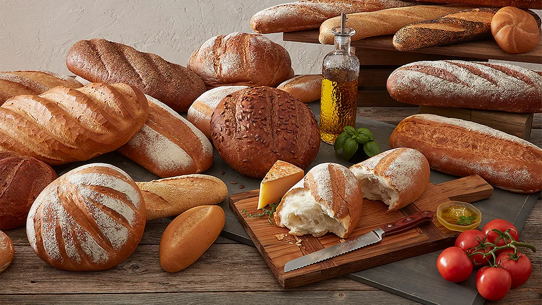 This image features a selection of rustic artisan breads, including crusty boules, baguettes, and loaves.
