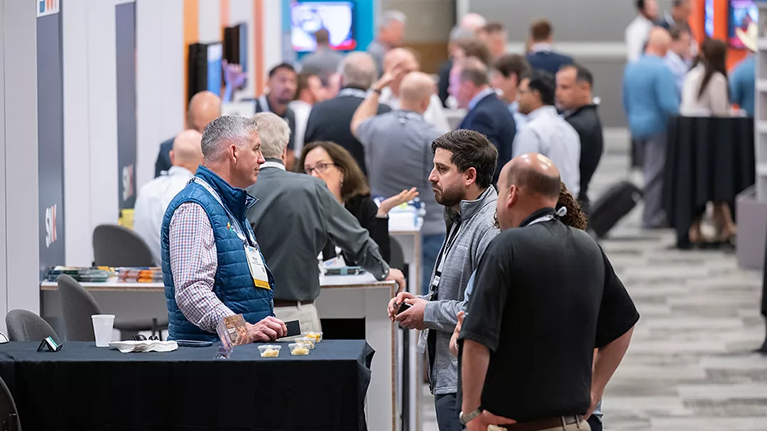 This image depicts a professional trade show, specifically the SNX event organized by SNAC International for the snack industry.