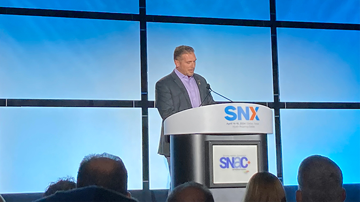 This image features a speaker presenting at the SNX event