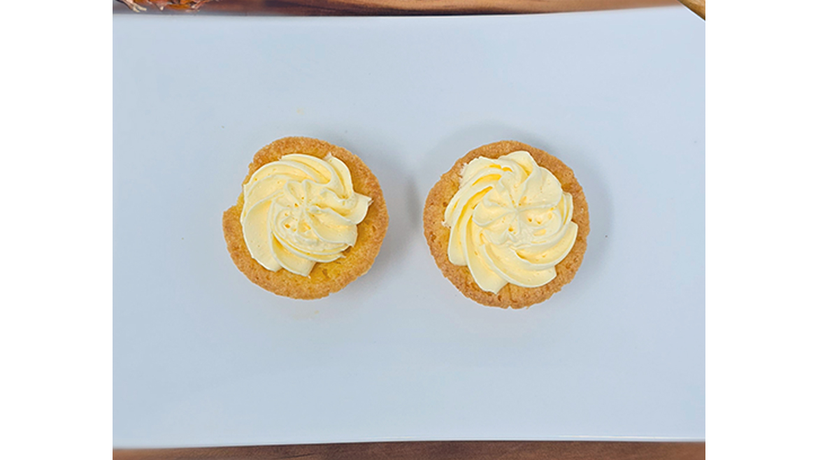 Two yellow cupcakes with butter-colored frosting shot from overhead