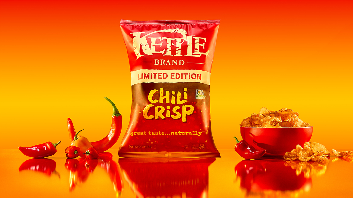 Red bag of LTO Kettle Brand Chili Crisp with chips in a bowl and chili peppers.