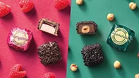 Wrapped and unwrapped chocolate pieces, berries, and nuts on pink and green background