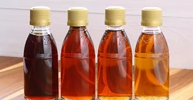 Four small bottles of different colors of maple syrup