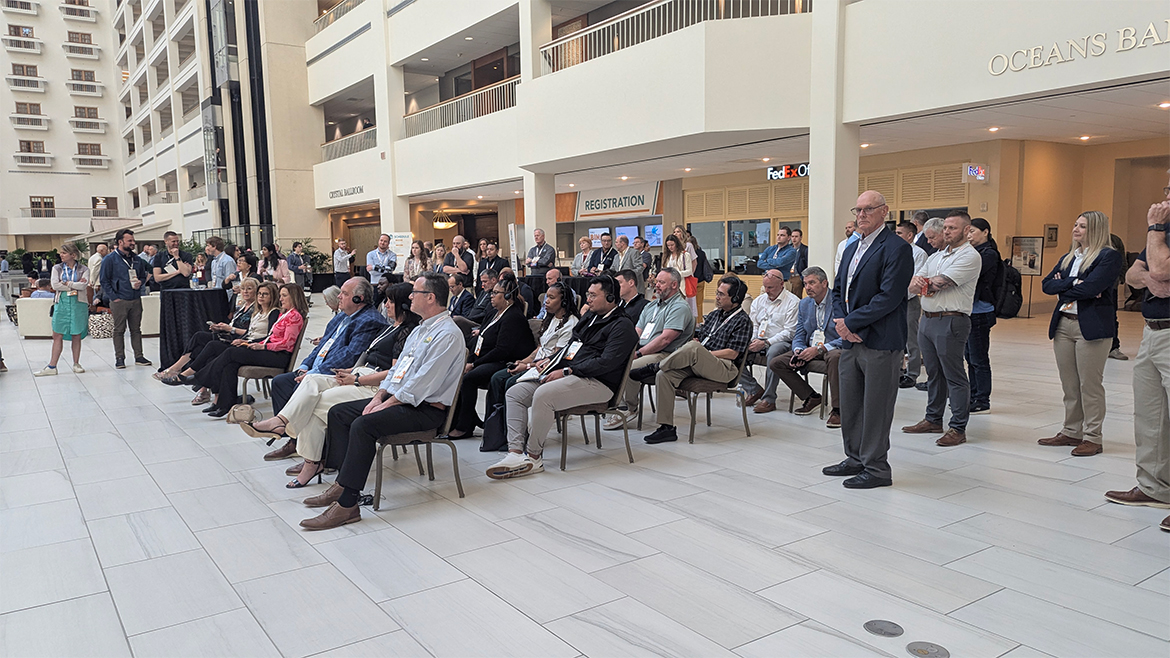 A group of people sit in a conference hall lobby