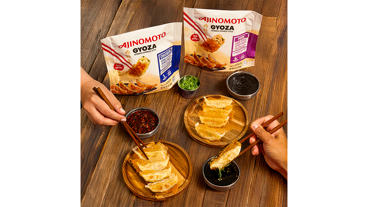 Two bags of Ajinomoto dumplings with chopsticks in hands, plus two plates and silver bowls with dipping sauces.