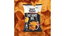 A black and white bag of Smash Kitchen Kettle Cooked Hot Honey BBQ chips, with chips in the background.
