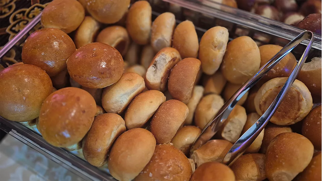 Basket full of round rolls with tongs