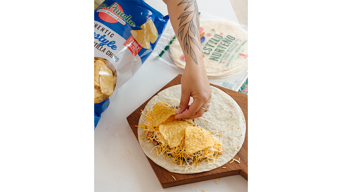 Hand making crunch wrap with tortillas and chips