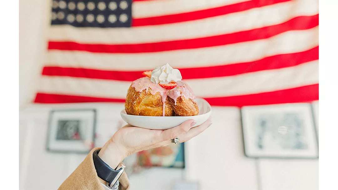 Hand holding up plated doughnuts in front of a U.S. flag