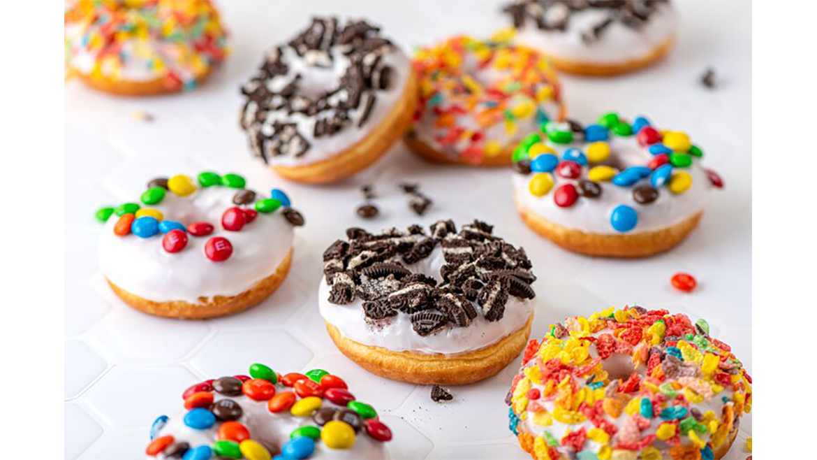 Assorted decorated cake doughnuts on white table