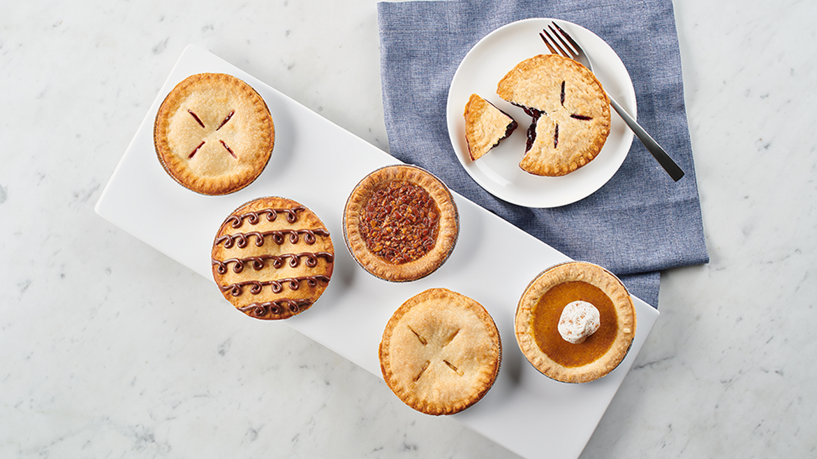 Assorted mini pies on a tray and plate, arranged on a table