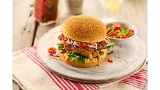Burger served on white plate on top of a decorated table Burger served on white plate on top of a decorated table