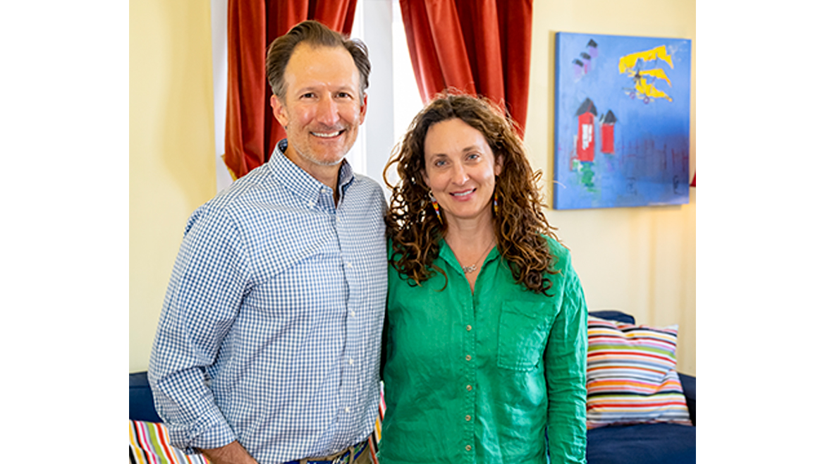 Scott and Megan Reamer in front of window with red curtains