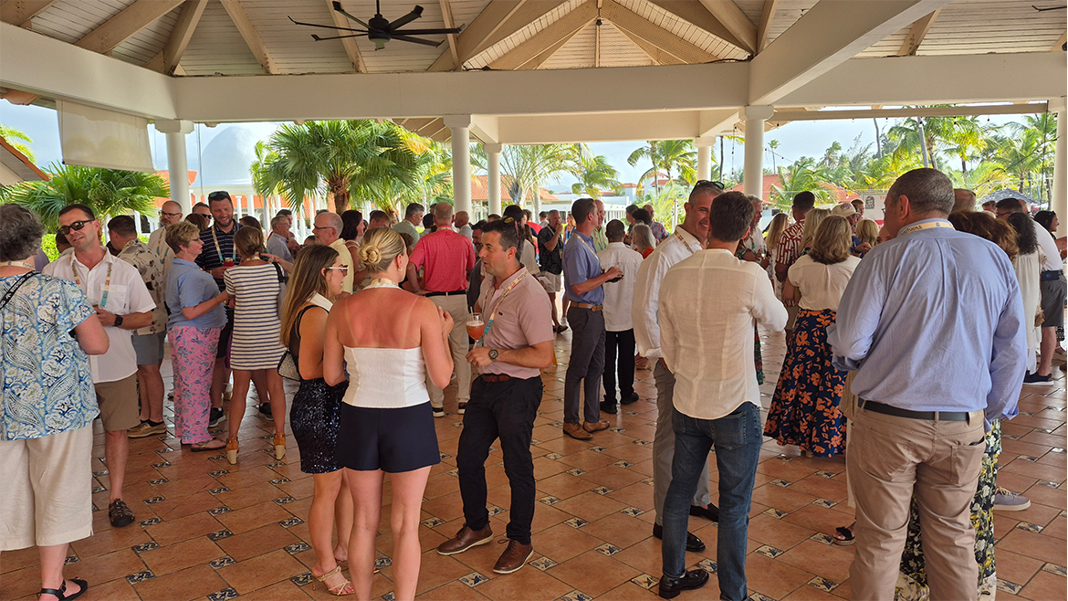Men and women wearing conference lanyards and casual dress congregate in an atrium.
