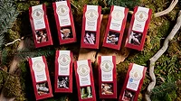 Ten red packages of Wildwood caramels, all different flavors, against a background of twigs and greenery. Ten red packages of Wildwood caramels, all different flavors, against a background of twigs and greenery.