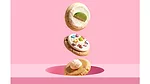 Three gravity-defying Crumbl cookies in front of pink background