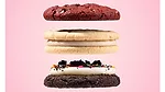 Three Crumbl cookies stacked in front of pink background