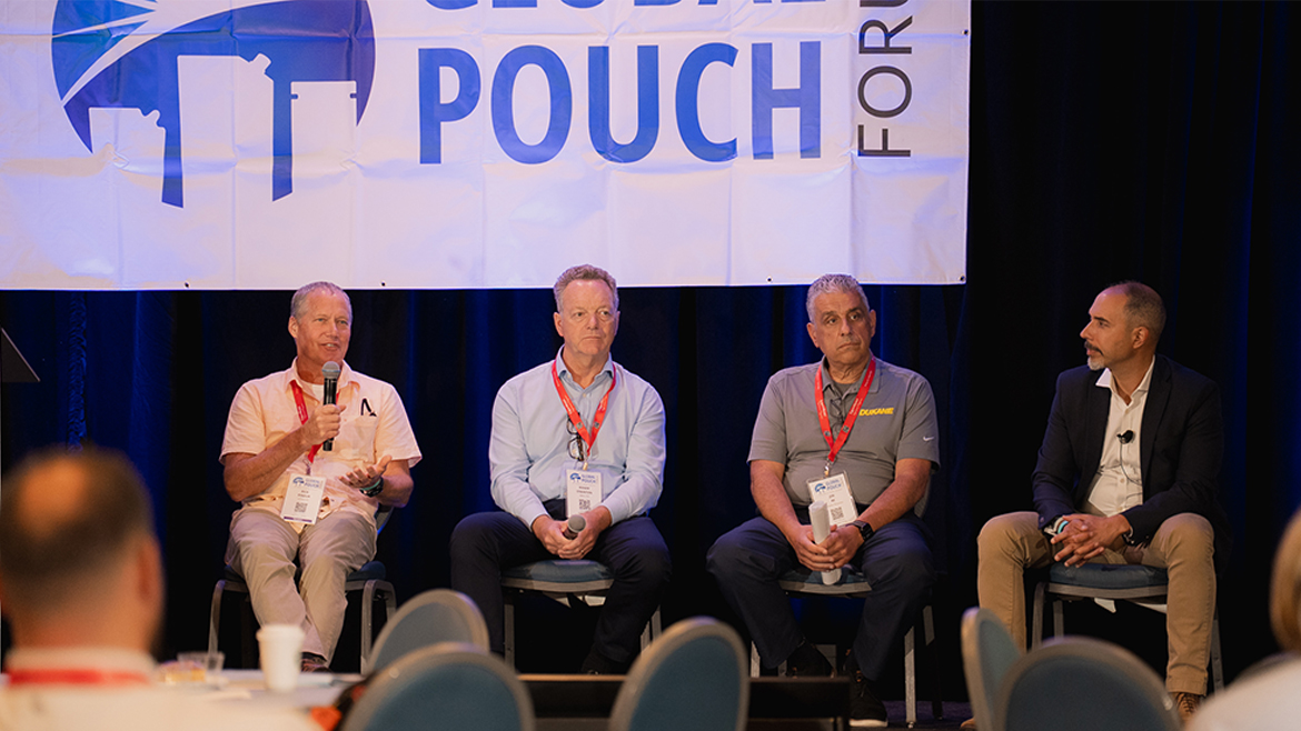 Four men sitting while wearing conference lanyards on a Global Pouch Forum panel.