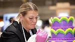 Woman decorating purple and green tiered cake