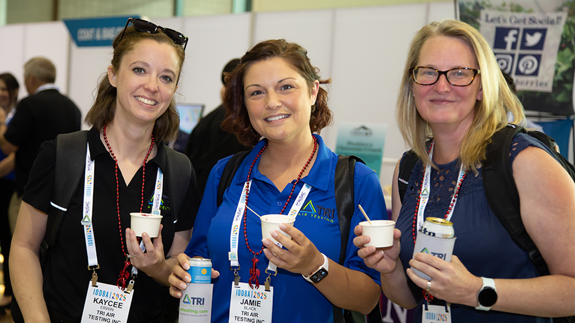 Three women wearing IDDBA badges at networking party
