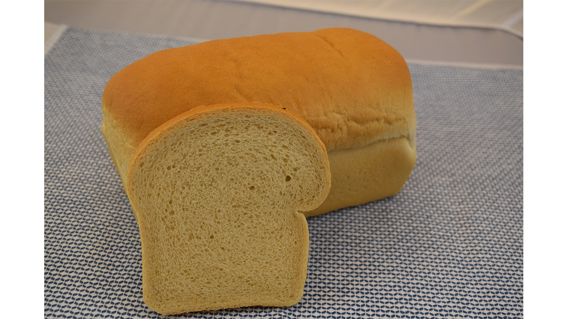 Loaf of bread with one slice in front on table
