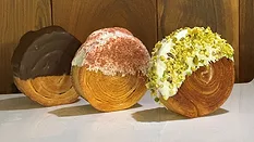 Three round sweet baked goods with different coatings on table