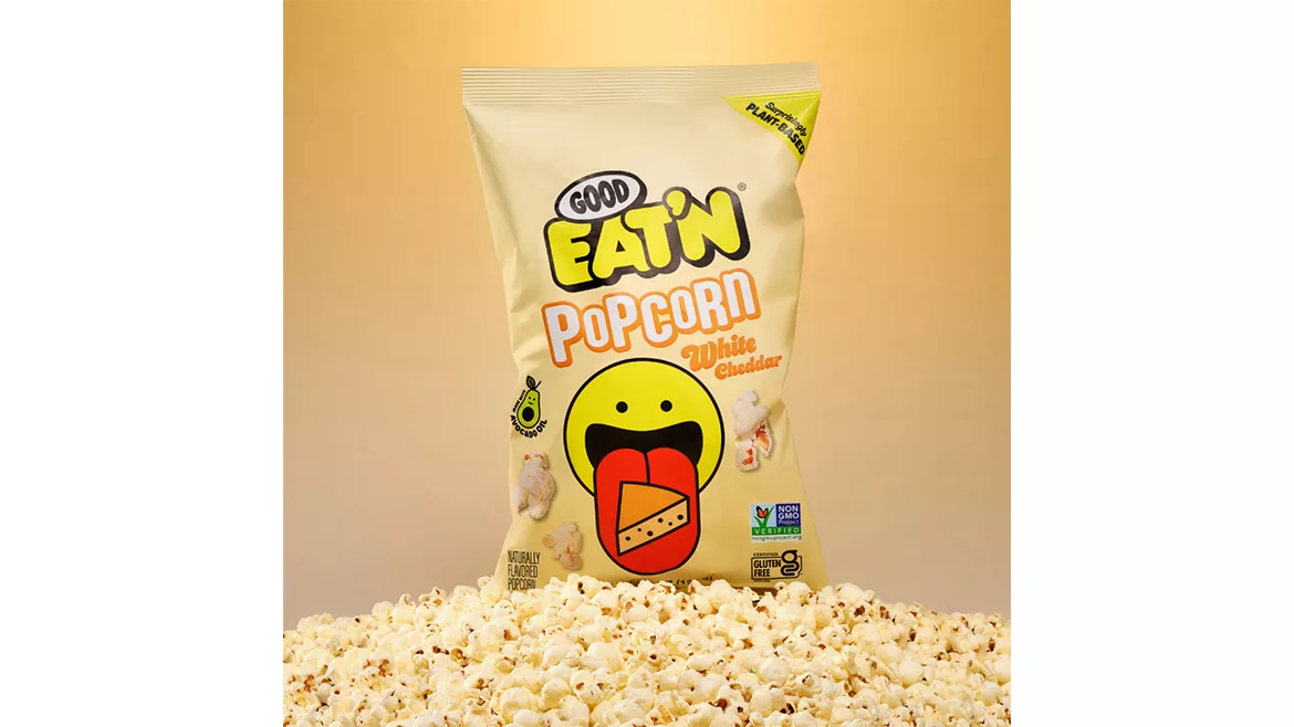A yellow bag of white cheddar popcorn with actual popcorn in front.