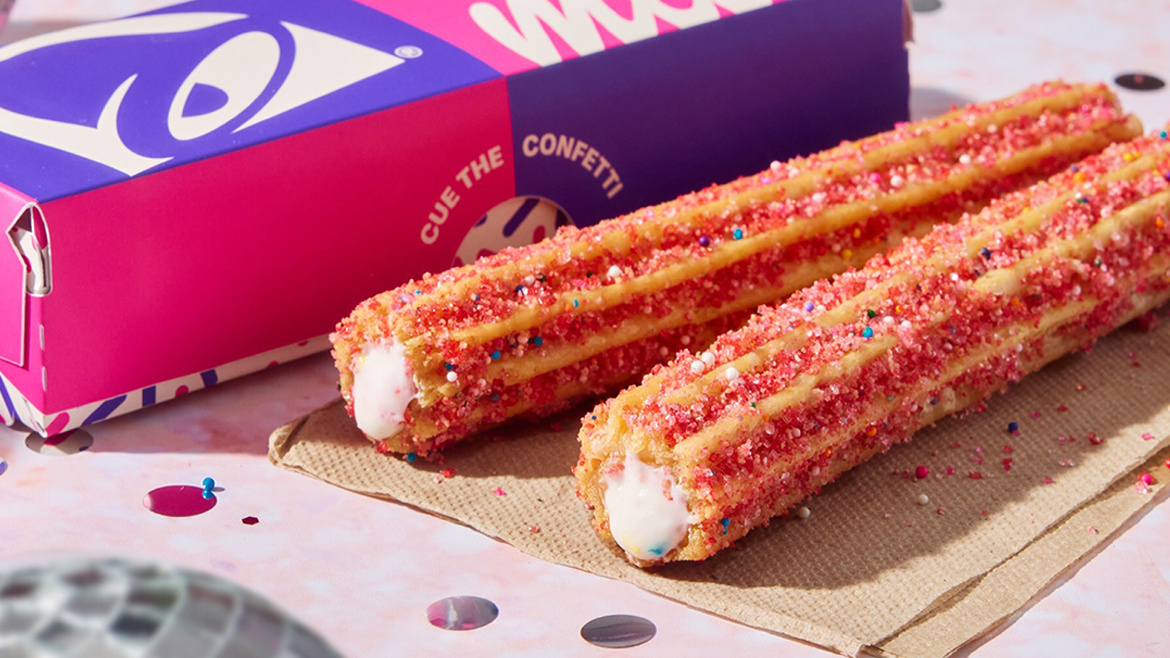 Bright pink Taco Bell x Milk Bar churro on table