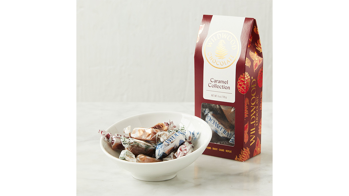 A box of Wildwood’s Caramel Collection, behind a white bowl filled with individually wrapped caramels.