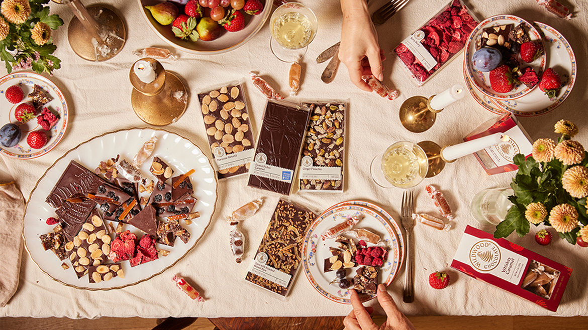A table filled with various Wildwood candy, including caramels in bags and unwrapped, plus chocolate bars in packaging and unwrapped.