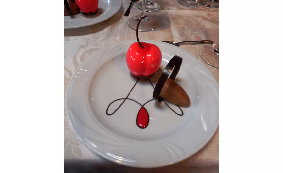 Plated dessert featuring a cherry jam-filled vanilla mouse  cherry accompanied by a chocolate mousse.
